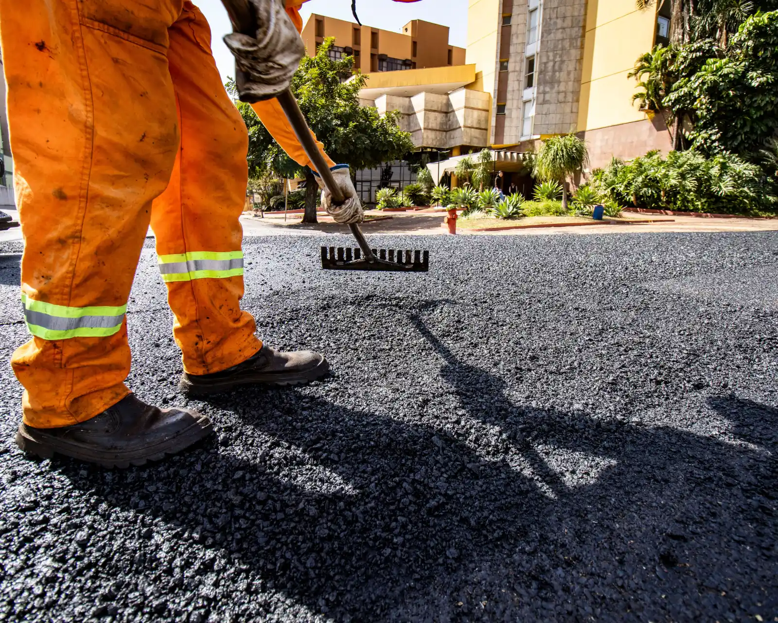 A paver working fresh asphalt level with a lute rake