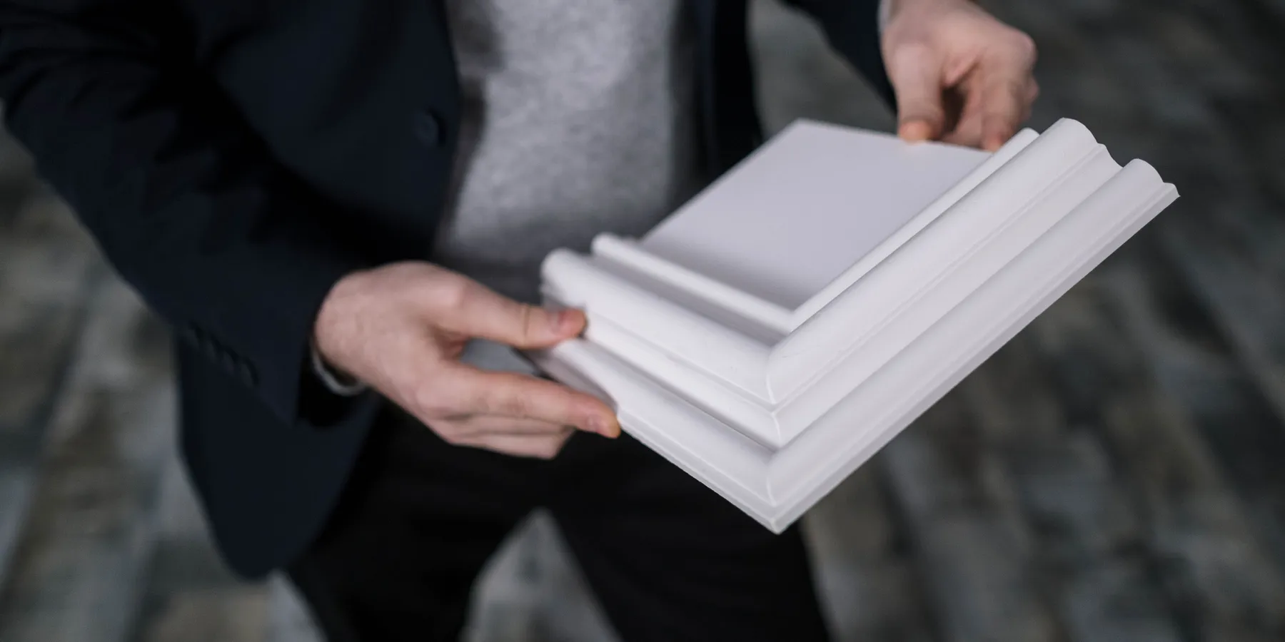 Hands holding white crown molding samples