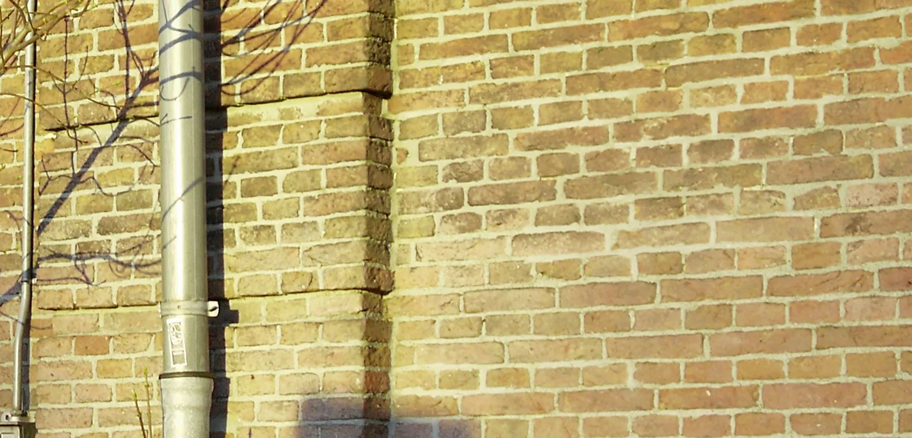 Sunlit brick wall laid in running bond with even mortar joints