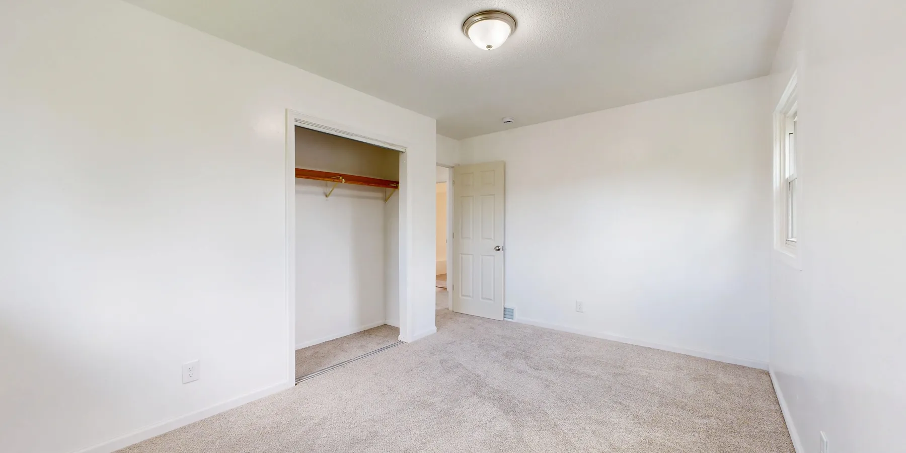 An empty room with plush carpet laid wall to wall
