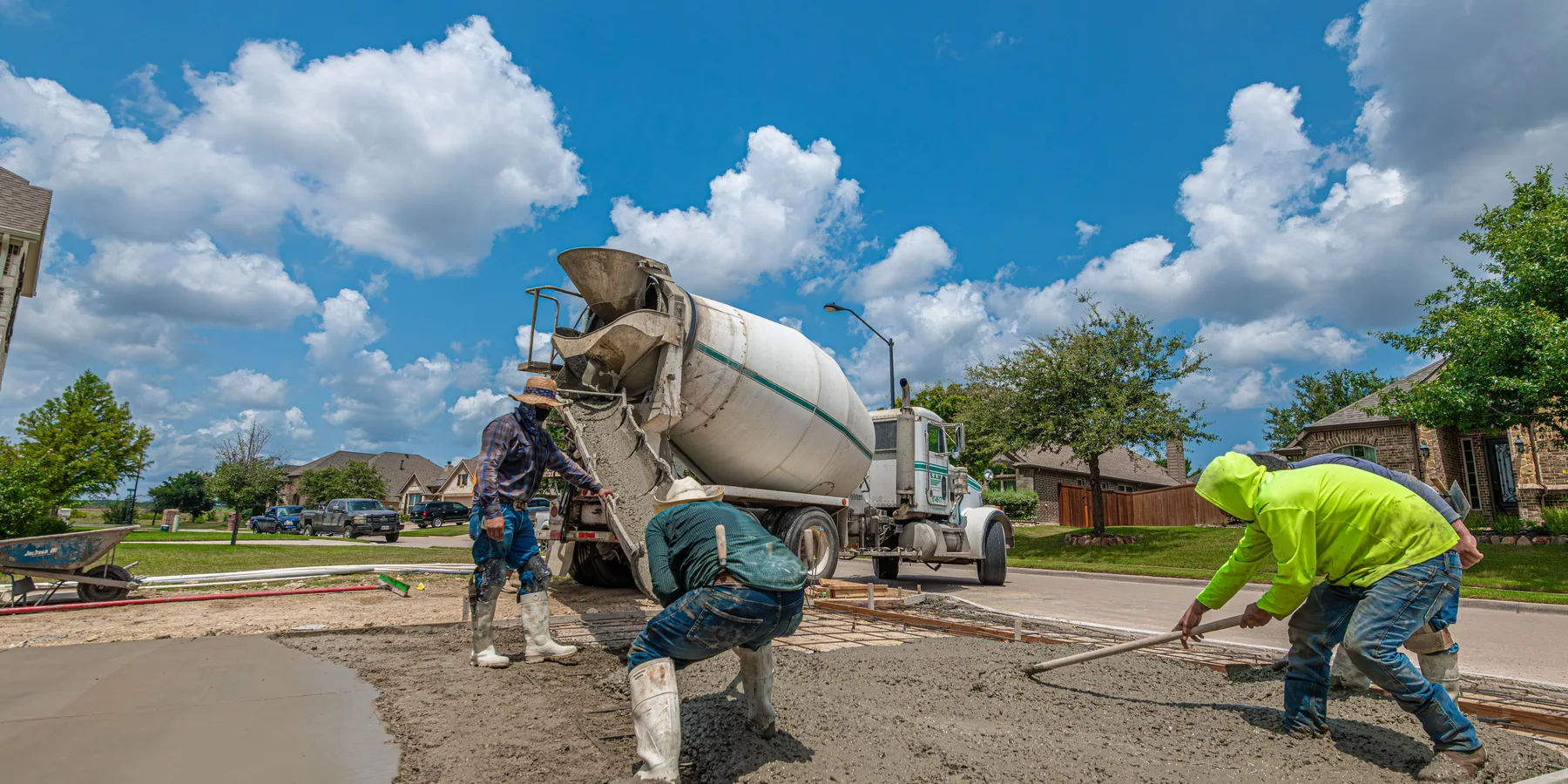 Crew placing fresh concrete for a driveway from a mixer truck