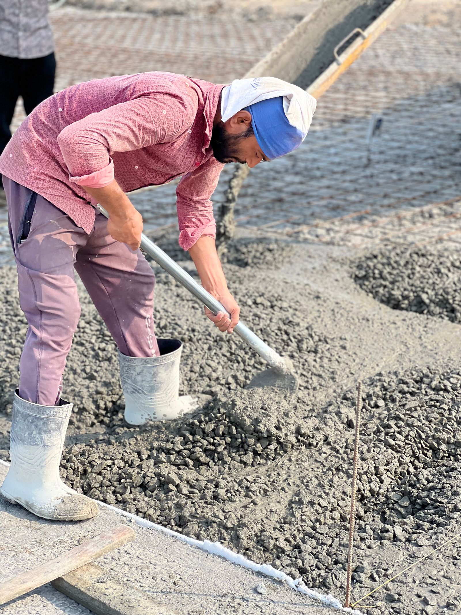 A worker spreading and levelling freshly poured concrete