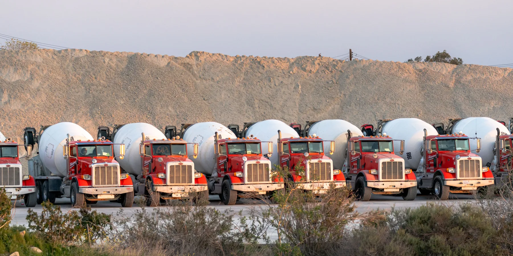A row of ready-mix concrete trucks waiting to load