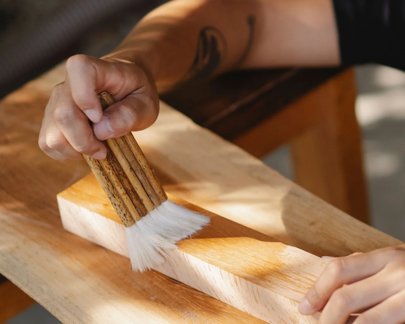 A brush laying finish along a wooden board