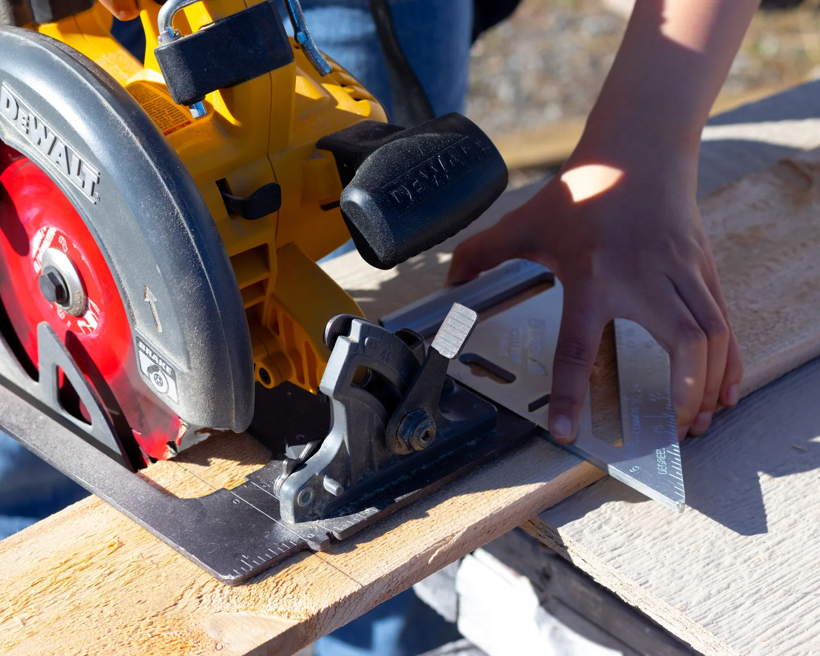 A framing square and saw beside a stair stringer being cut