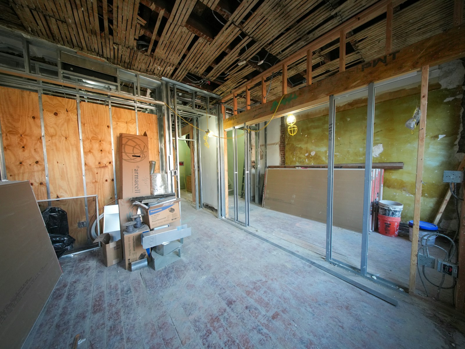 A metal-stud partition frame with drywall boards being fitted