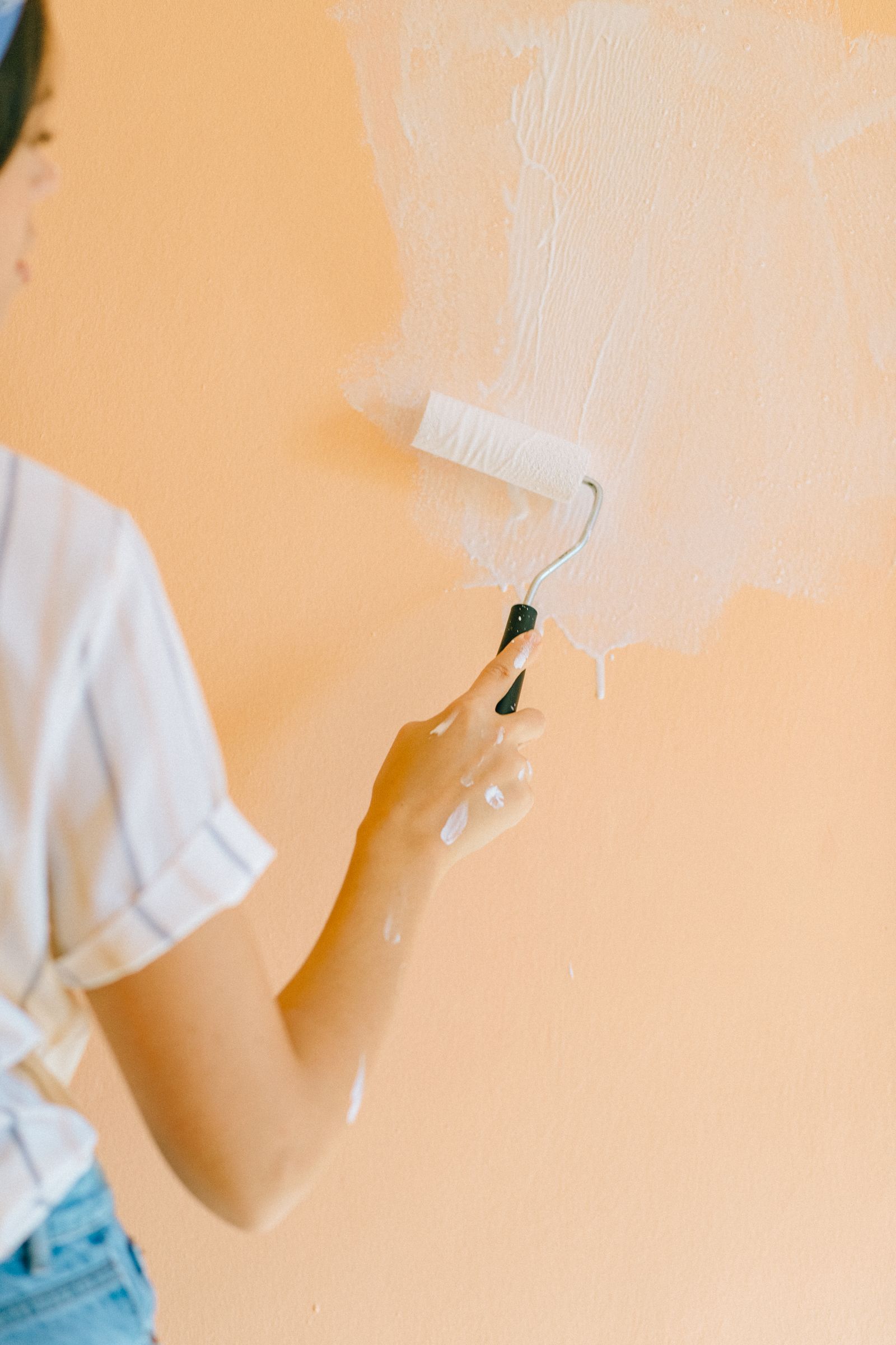 Hand rolling warm paint across a wall that is almost fully coated