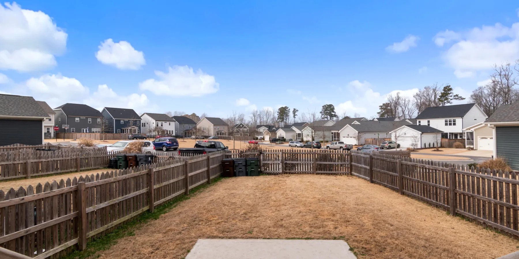 A wood picket fence around a backyard, its posts and rails showing