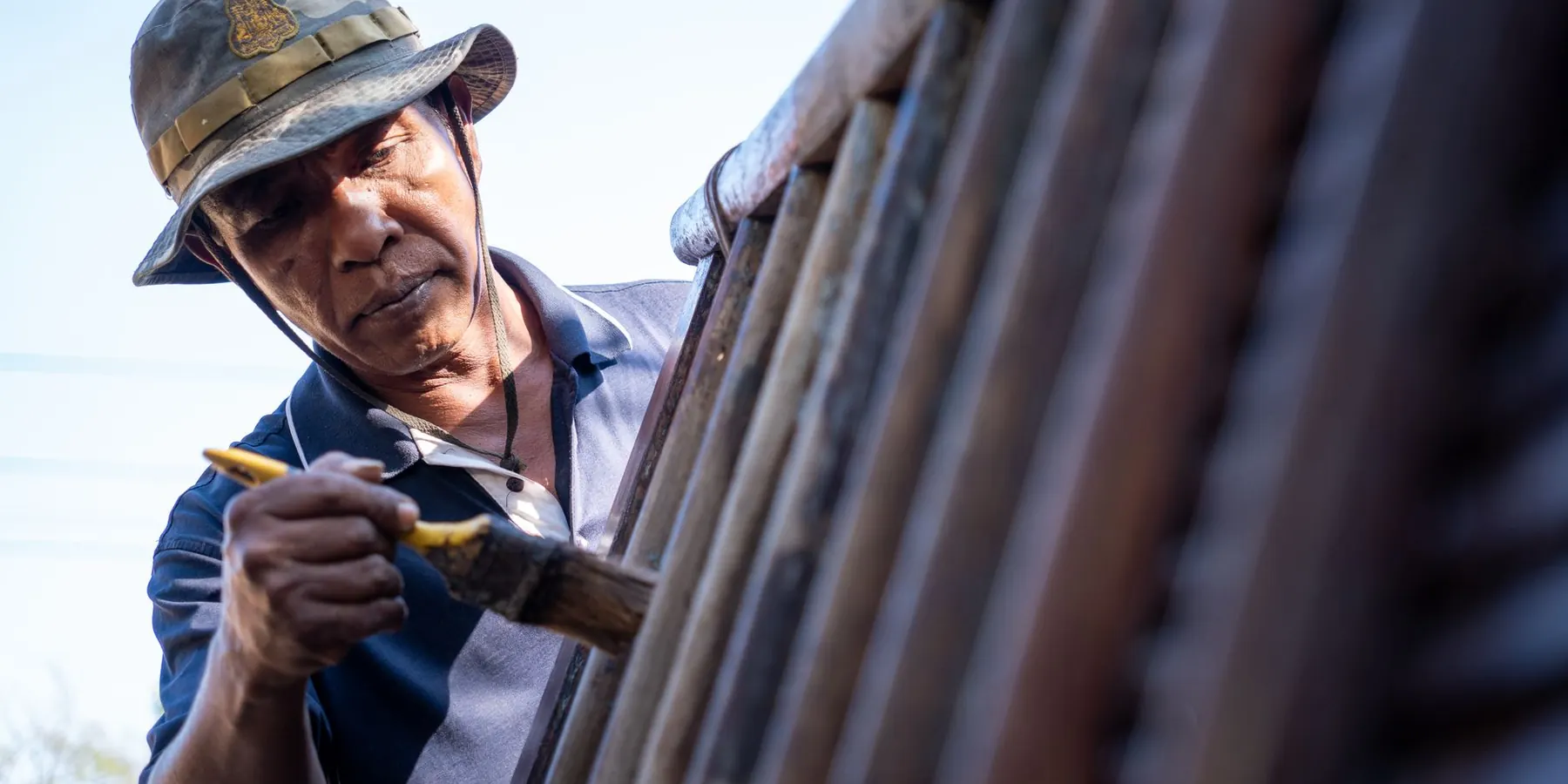 Man brushing stain onto a wooden fence