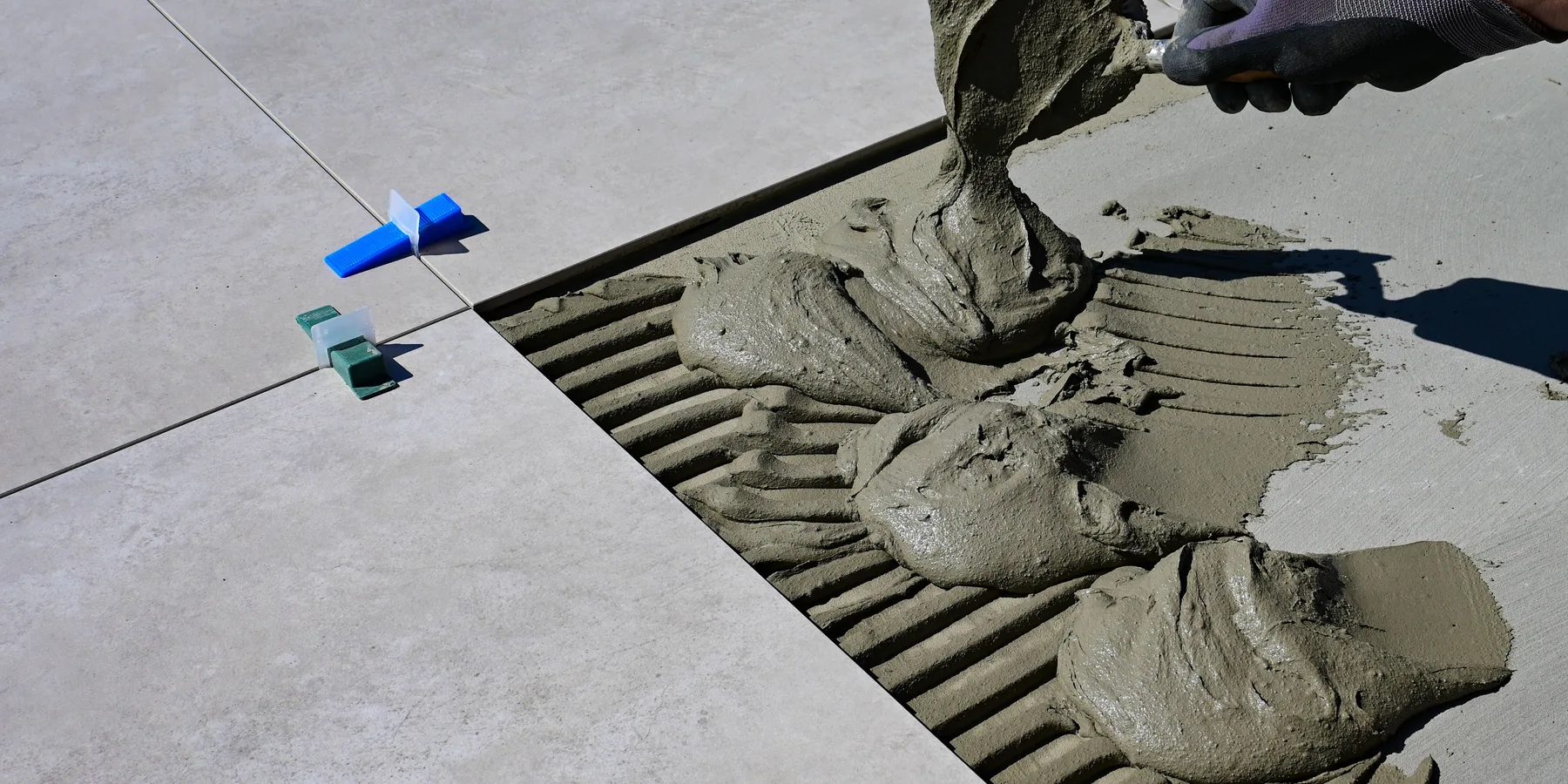 Gloved hand spreading mortar for a tile installation