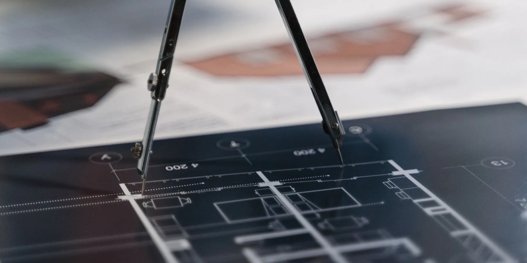 A drawing compass resting on a technical diagram