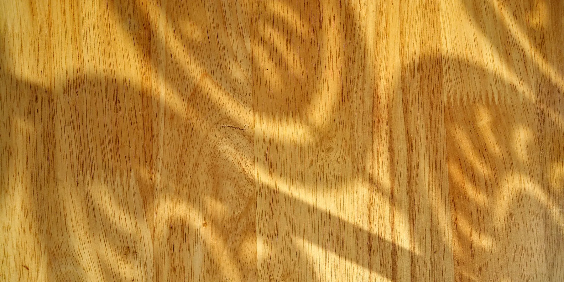 Solid hardwood boards being nailed down across a floor