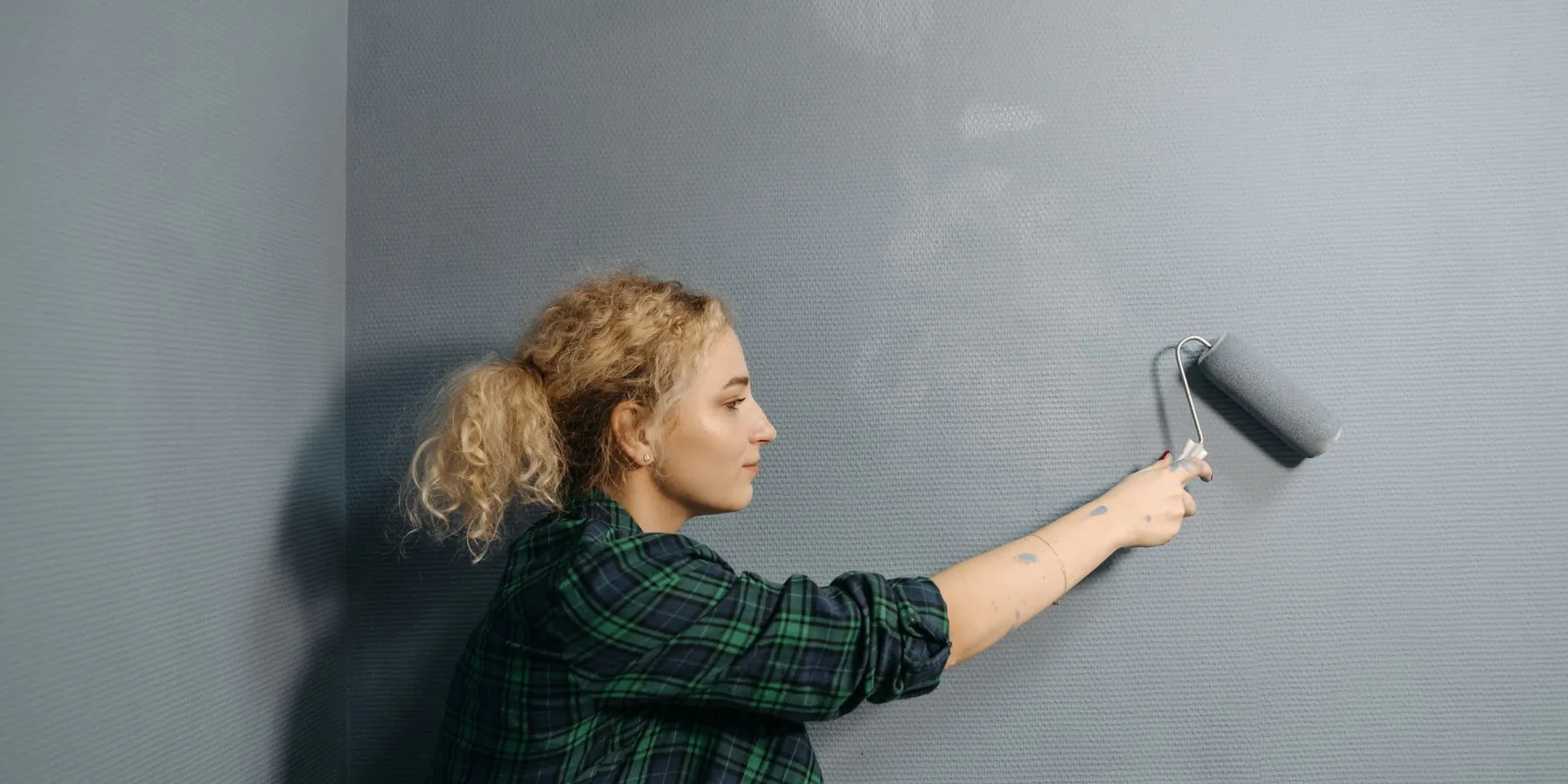 Woman rolling gray paint onto an interior wall