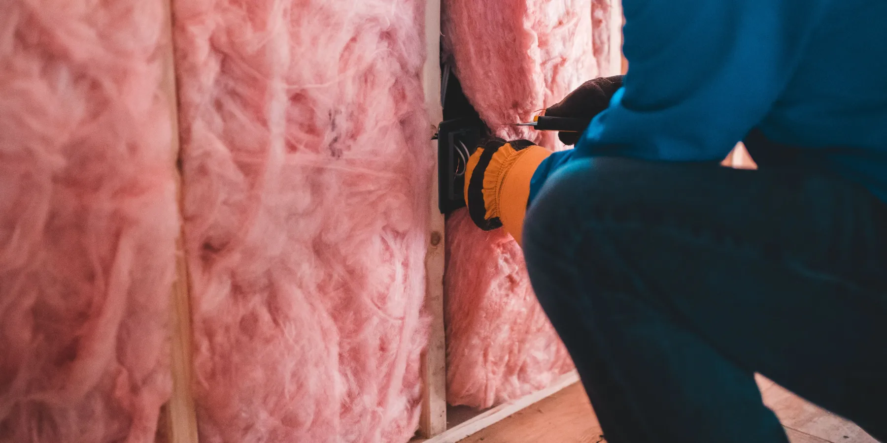 Pink fiberglass insulation batts fitted between wall studs
