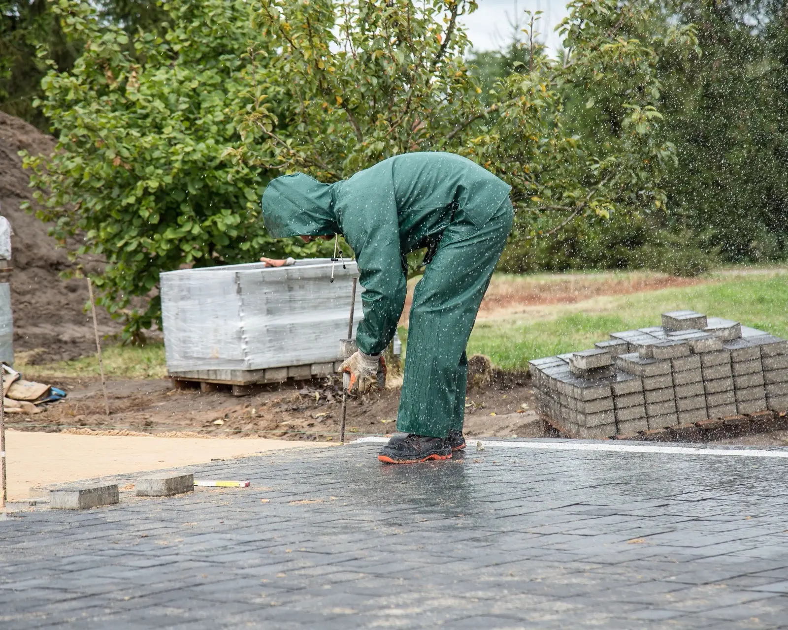 A worker laying paving stones by hand