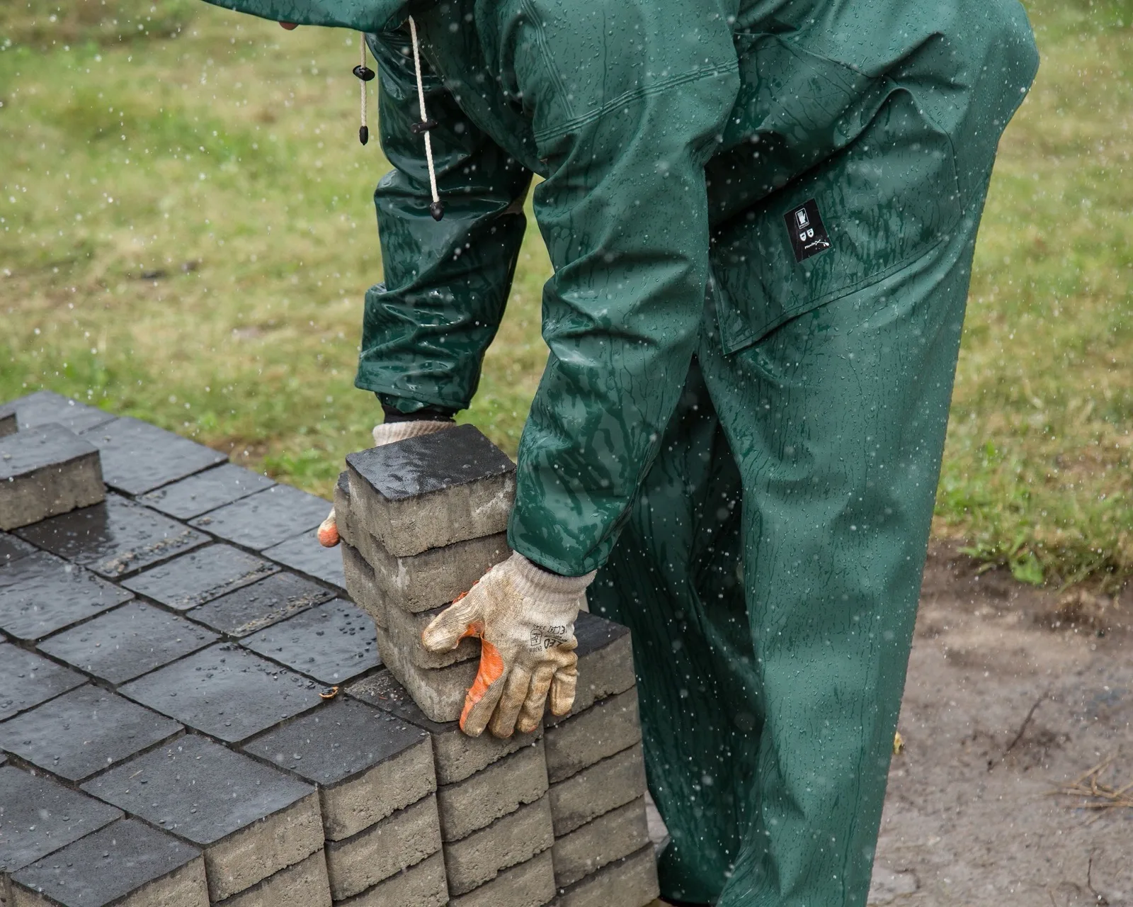 Pavers stacked beside a plate compactor and screed rails
