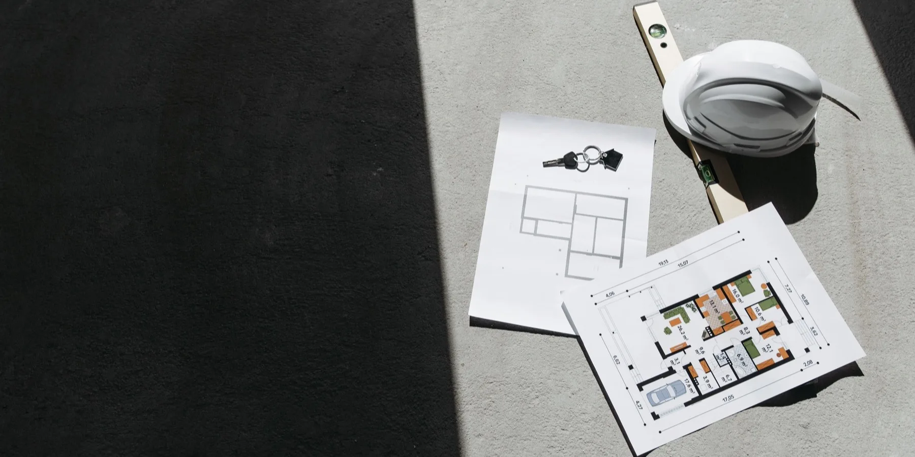 Site drawings, a hard hat and a spirit level in sunlight