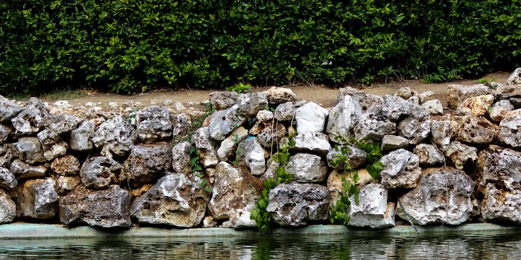 A stone retaining wall holding back a planted bank