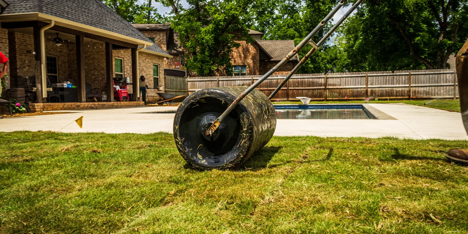 A worker unrolling fresh sod in a backyard