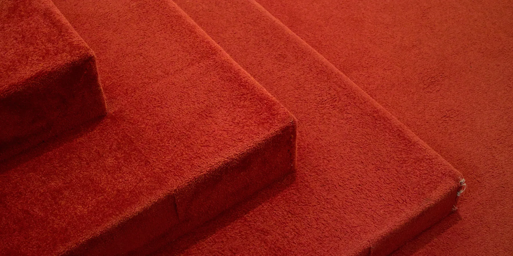 Close-up of red carpet wrapped over the nosing of three stair steps