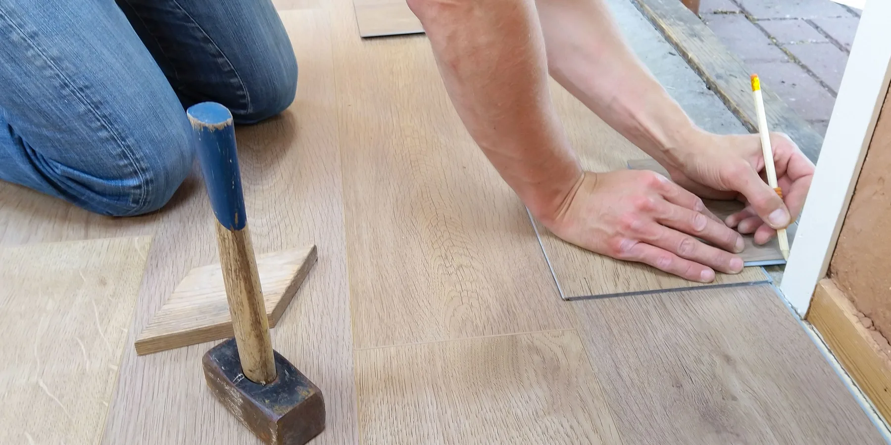 A fitter marking a plank floor before cutting it to length