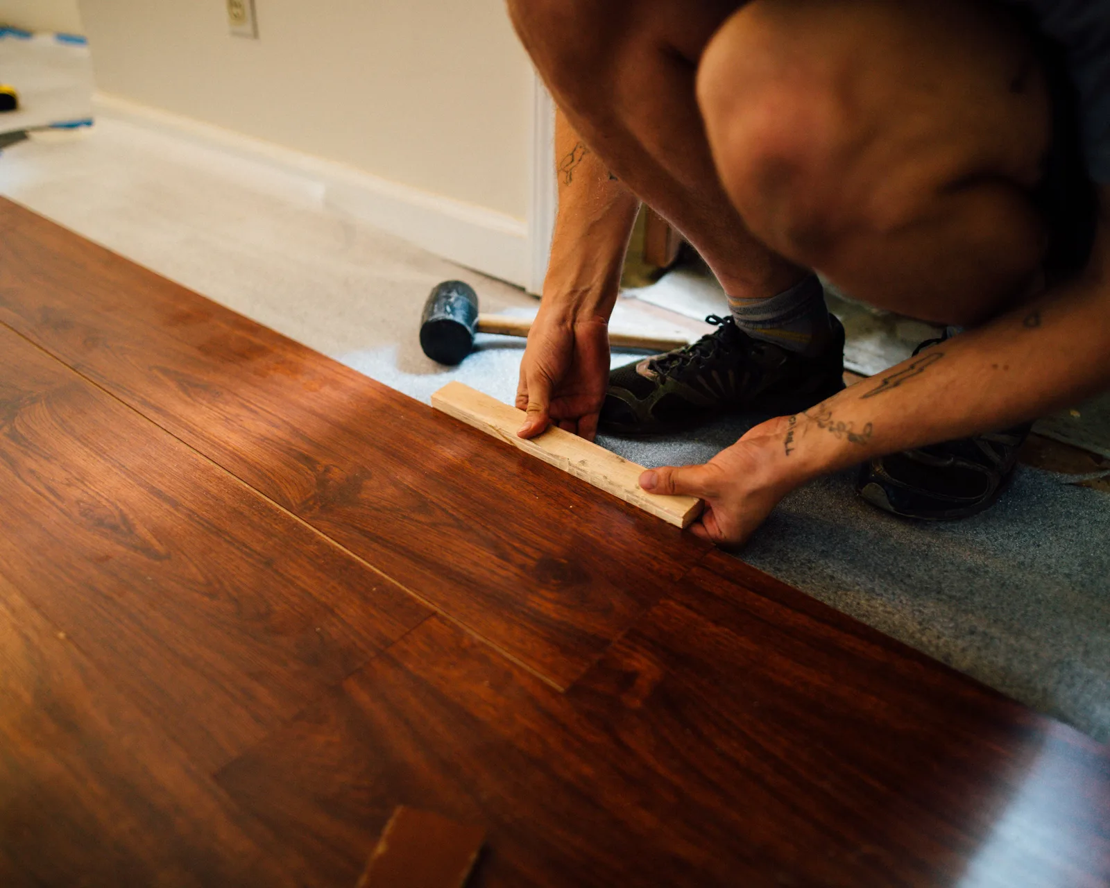 A fitter tapping a plank floor together on the subfloor